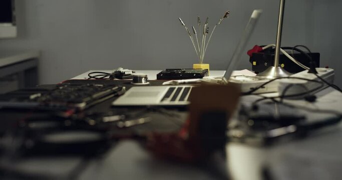 Computer hardware, empty workshop and repair garage for maintenance support, electronics or services. Information technology, night and workplace desk for fixing laptop, equipment or IT in tech lab