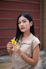 A teenage girl wearing a vintage dress holds a yellow flower and turns to look at you with haughty eyes.
