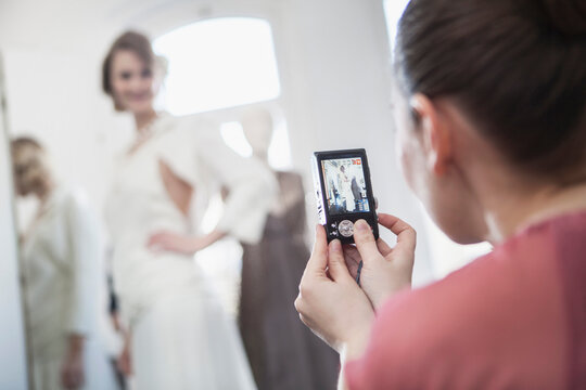 Fashion designer taking a picture of a wedding gown on a beautiful woman. Munich, Bavaria, Germany