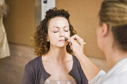 Hair and make-up artist applying foundation on a beautiful woman's face. Munich, Bavaria, Germany