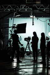 Silhouette people working in studio with equipment and lighting for making movie or commercial	