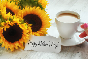 Happy Mother's Day card message in sunflower bouquet left next to morning coffee