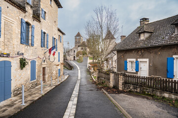 french village street with church and stone house in the background.