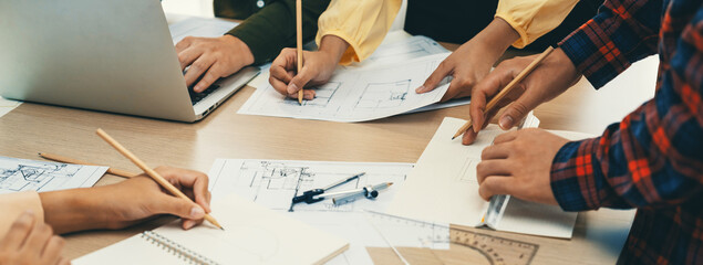 Skilled architect team using architectural equipment during colleague discussion about building design at meeting table with blueprint scatter around. Closeup. Focus on hand. Delineation. - obrazy, fototapety, plakaty