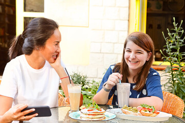 Cheerful multiethnic women enjoying lunch in outdoor cafe
