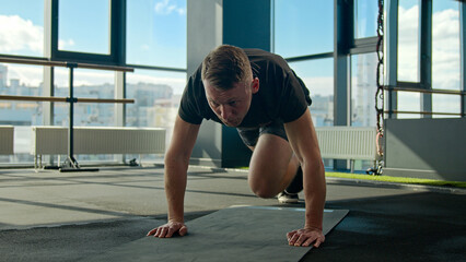 Caucasian sportsman sport trainer doing mountain climber exercise running plank on fitness mat male athlete runner bending knees strong man training endurance healthy lifestyle cardio workout in gym