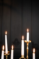 Lighted tall candles on the background of a luxurious black wall