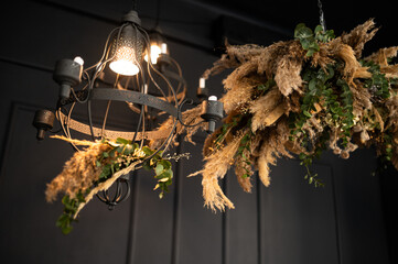 Hanging installation of dried flowers against the background of a luxurious black wall