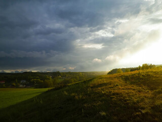 Stormy couds and sunset sky over fields.