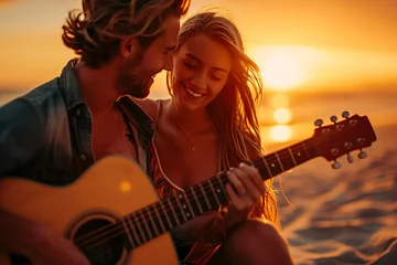 Fototapeten a young happy couple with guitar sitting on a exotic sunset beach © CROCOTHERY