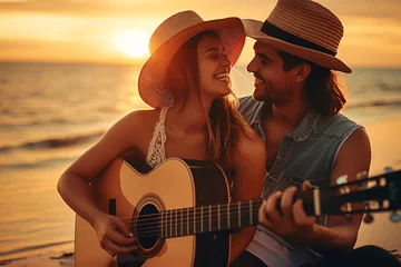 Selbstklebende Fototapeten a young happy couple with guitar sitting on a exotic sunset beach © CROCOTHERY
