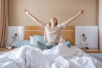 Woman stretching in bed after wake up - obrazy, fototapety, plakaty