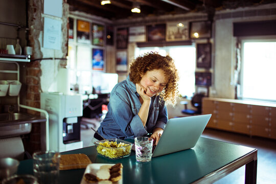 Young woman using a laptop while on her lunch break while working in a startup company office