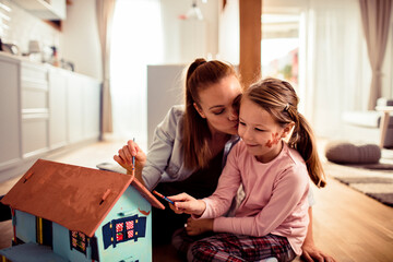 Mother and daughter enjoying crafting a dollhouse together at home