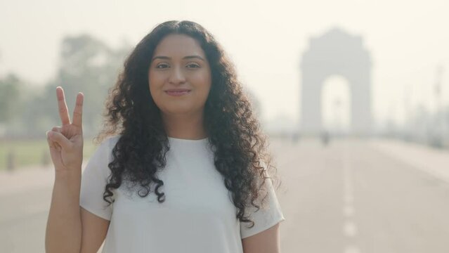 Indian Girl with Curly Hair Showing Victory Sign at India Gate