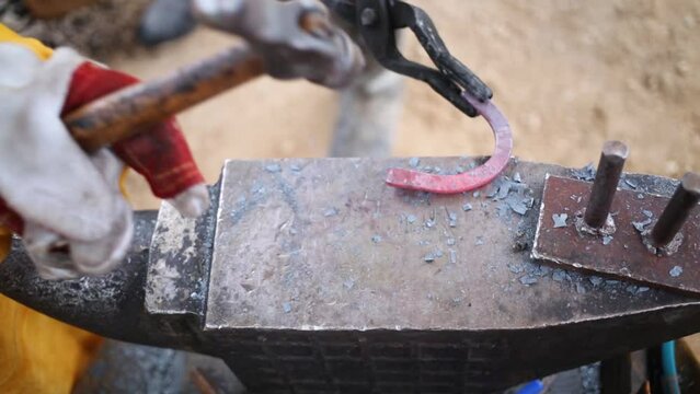 Hands of two children making horseshoe in blacksmith workshop