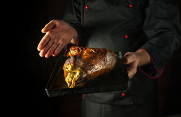 Baked duck carcass on a baking sheet in the hands of a chef. Concept of cooking delicious poultry....