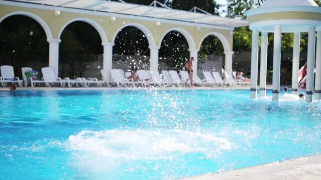 Boy and girl jump to pool with pure water with Jacuzzi