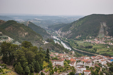Fototapeta na wymiar Aerial view of Mondego river in valley and architecture of Penacova village with gradient mountains in horizon, PORTUGAL