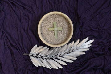 Palm cross, ash and silver palm leaf on purple background. Ash Wednesday concept.
