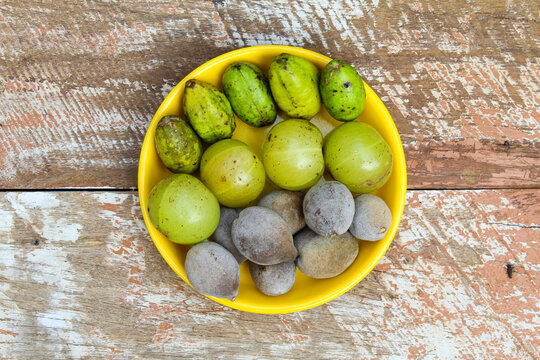 Indian gooseberry,Terminalia bellirica and Terminalia chebula fruits in a plate on wooden background top view 