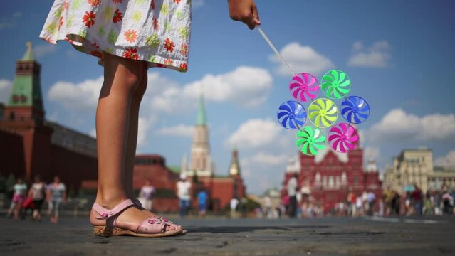 Legs of girl with pinwheel on Red Square at summer day