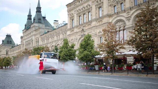 Watering truck on street and woman have fun at summer
