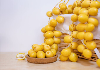 Close up and selective focus fresh dates fruits in wooden plate.
