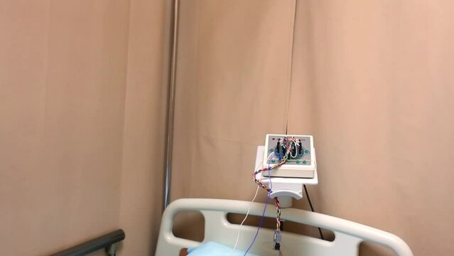 Bed with pillow and electroencephalograph in hospital ward.
