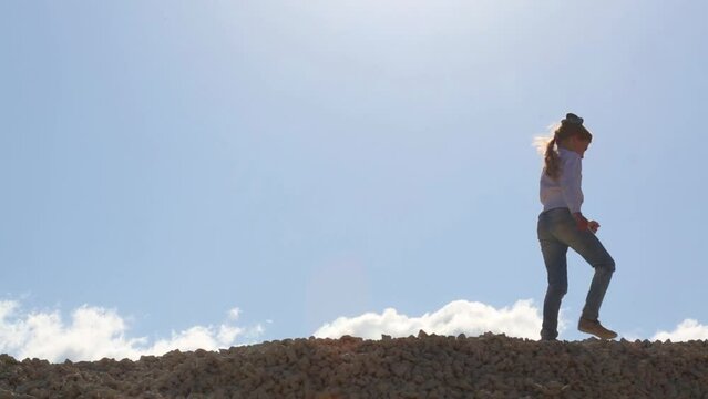 Girl and boy in jeans go on stone pile at sunny day