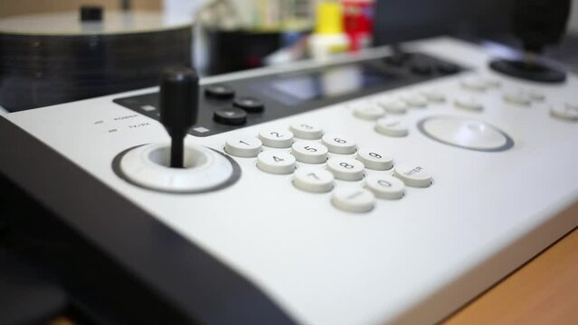 Close-up remote control panel with joystick and ring at desk.