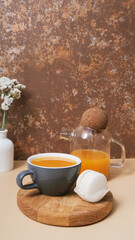 Cup and teapot of sea buckthorn tea and macaroon. Cozy autumn winter still life