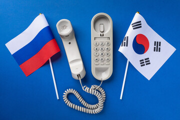 Old telephone and two flags on a blue background, concept on the theme of telephone conversations...