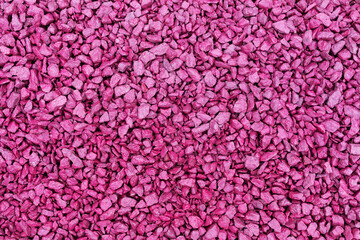 Flat background of small stones painted in fuchsia color