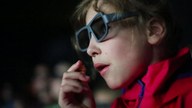 Little girl watch a movie in 3D glasses at the cinema.