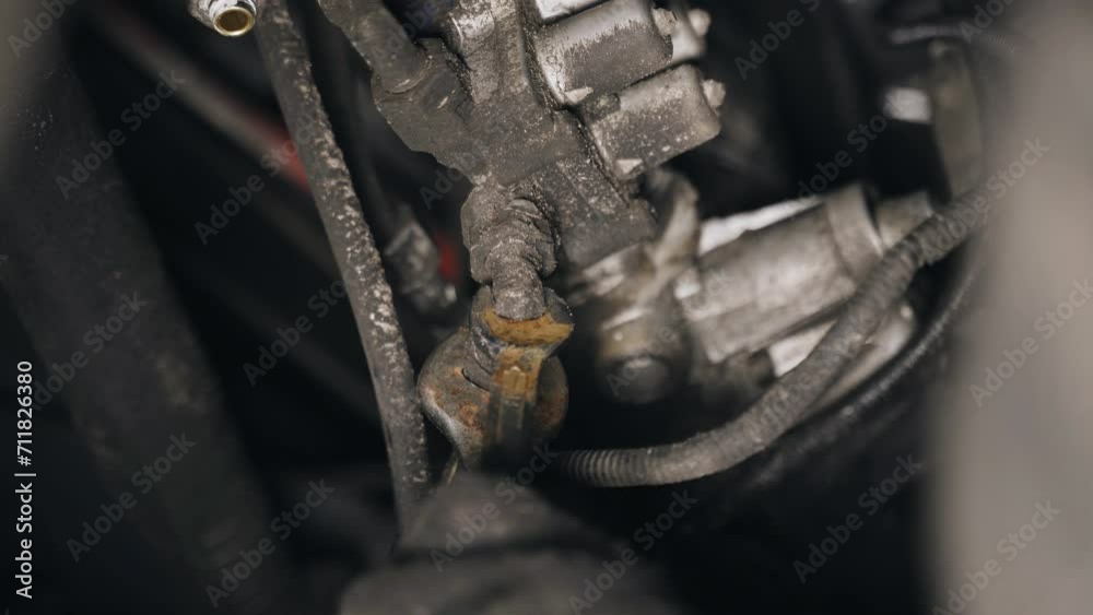 Poster A mechanic unscrews the nuts with a tool to remove a part attached to the chassis of a truck. Close-up.