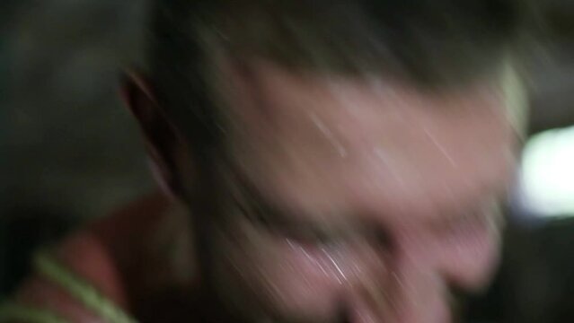 Intense sweaty face of young muscular man pulling rope