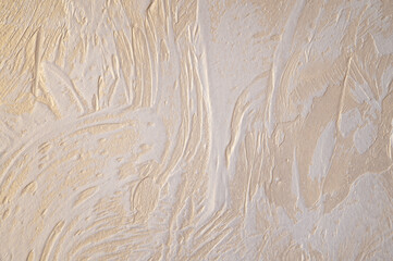 Wall with decorative plaster. Gold glossy plated with white relief pattern.