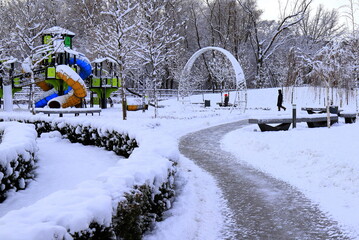 Winter park square street with children s playground, covered with snow. Children's slides and...