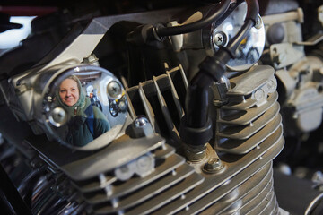 visitor is reflected in the engine of a vintage motorcycle in Denmark