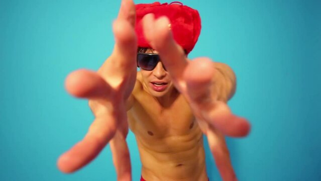 Half-naked guy in fur cap dances with his hands closely to camera