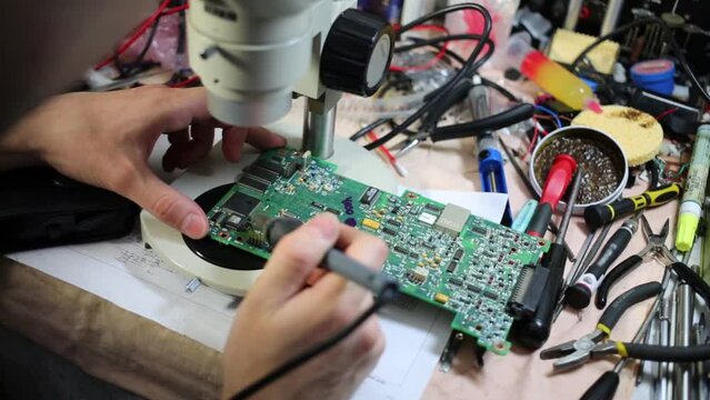 Man looks at motherboard through microscope and brazes