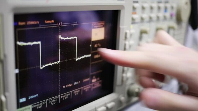Digital oscilloscope and male hand turns tumblers for setting