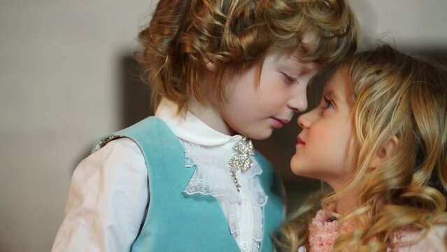 Little cute boy and girl in medieval costumes touch noses