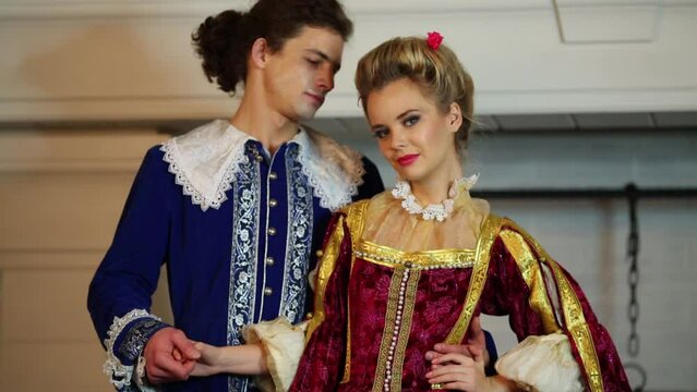 man and woman in medieval costumes smile and look at each other