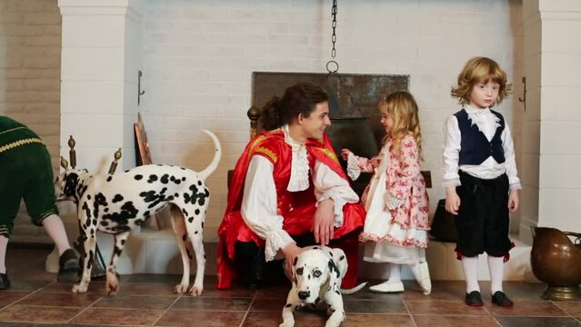 Father with three children and three dalmatians sit near chimney