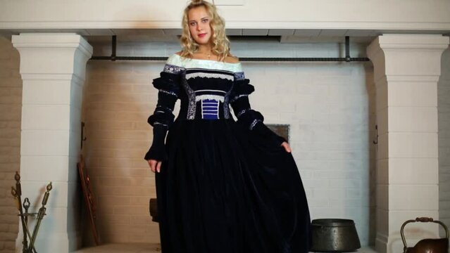 Beautiful woman in medieval costume dances near fireplace