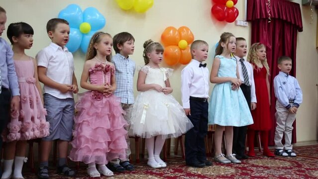 Eleven little boys and girls speak and spin in hall of kindergarten