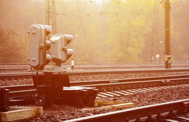 Photo of a fragment of a railway track with a small traffic light in rainy weather