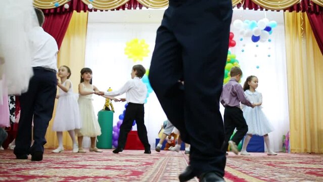 Twenty four boys and girls dance in pairs in kindergarten holiday